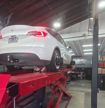 White car on hydraulic lift at POPS FULL SERVICE auto repair shop.