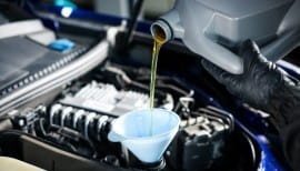 Mechanic pouring engine oil into car engine during oil change.