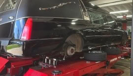 Black luxury car on lift at POPS FULL SERVICE auto repair shop.