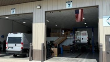 Auto repair shop service bay with vehicles and tools.