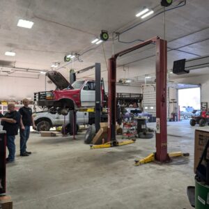 Auto repair shop with vehicle lift and mechanics working on trucks.