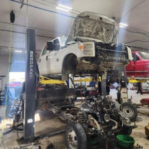 Car repair shop with vehicle on lift and engine removed.