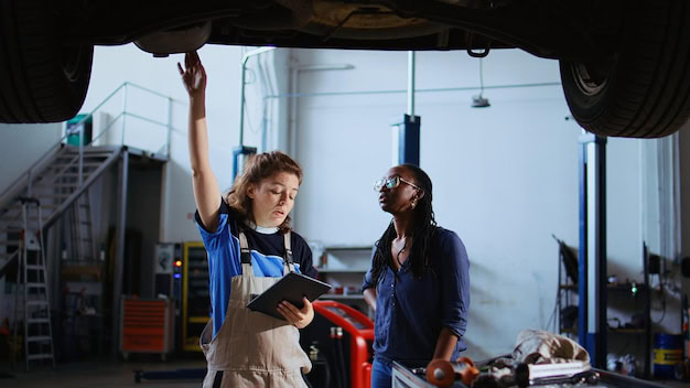 Mechanic and customer reviewing repair needs under a car