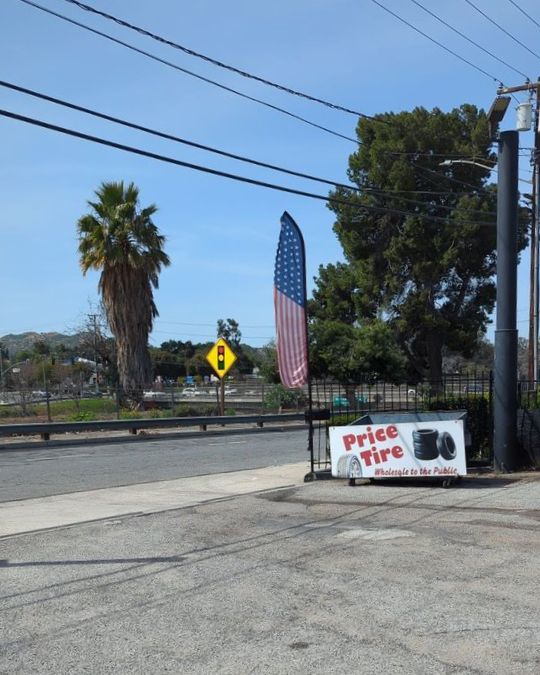 Price Tires & Wheels shop with American flag and tire sign in the background.