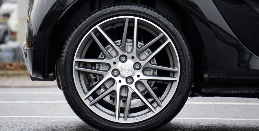 Close-up of a car tire and alloy wheel on asphalt road.