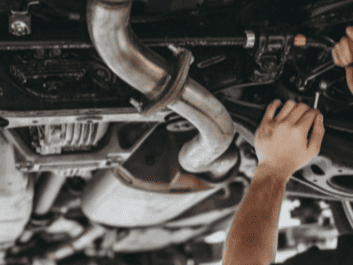 Mechanic inspecting vehicle undercarriage for auto repair and maintenance.
