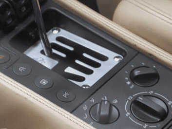 Close-up of car gear shift panel with climate controls and gear lever.