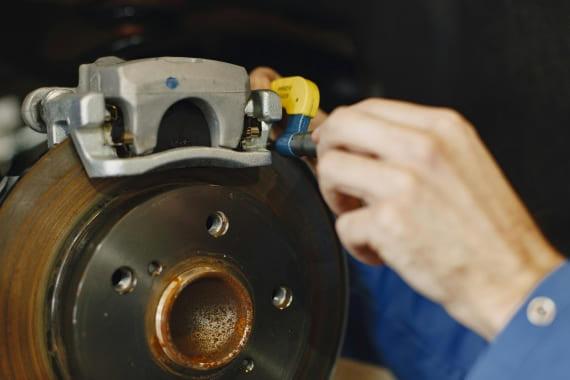 Mechanic inspecting brake rotor and caliper for vehicle maintenance and repair.