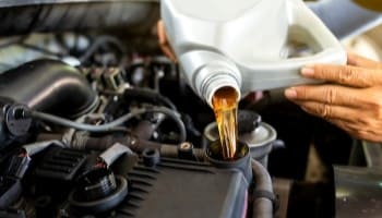 Engine oil being poured into a car engine during maintenance.