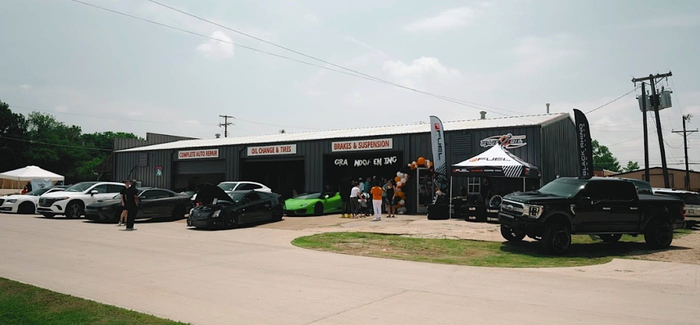 Qwik Oil & Auto Care auto repair shop with multiple cars parked outside, including sports cars and t.