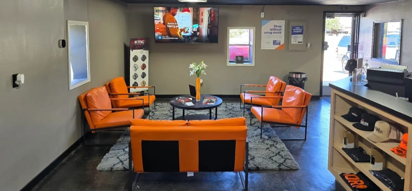 Interior waiting area at Qwik Oil & Auto Care with comfortable orange seating and a flat-screen TV.