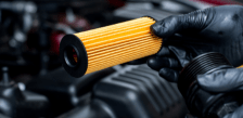 Technician holding a new oil filter for vehicle maintenance.