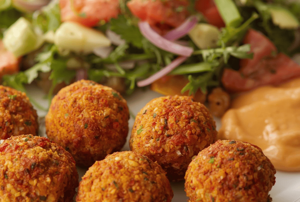 Kuvani falafel kuglice sa salatom i humusom, zdrava opcija za energičan dan.