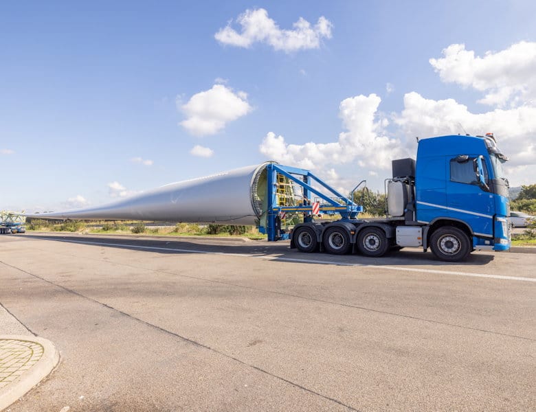 Wind turbine blade transport on a flatbed truck en route to renewable energy project site.