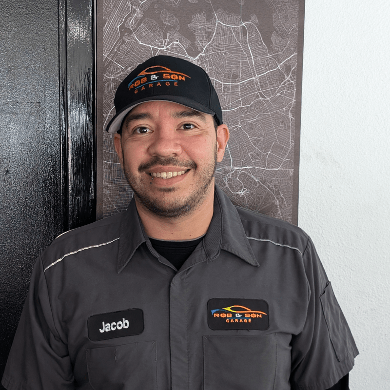 Friendly technician at Rob & Son Garage wearing uniform and cap.