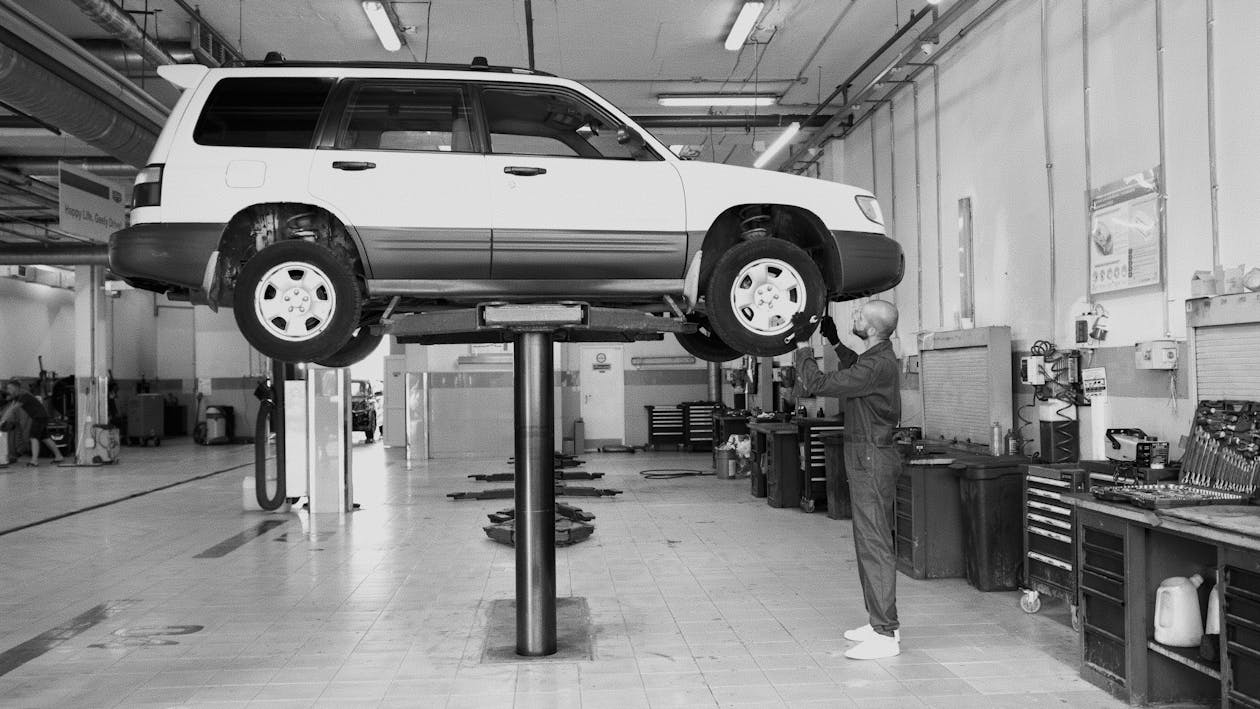 Car lifted on hydraulic lift during vehicle inspection at Rob & Son Garage.