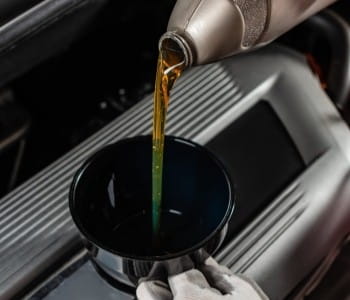 Pouring fresh motor oil into a car engine during oil change.