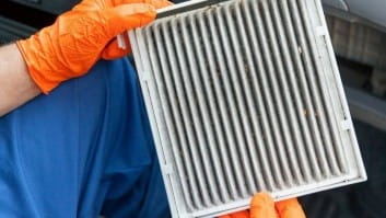 Auto repair technician inspecting a car air filter for maintenance or replacement.