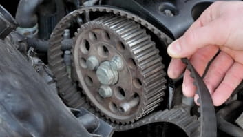 Close-up of a mechanic installing a timing belt on a car engine.