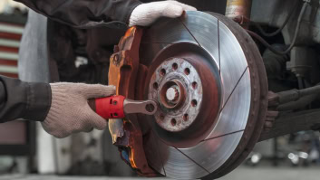Technician inspecting a car's brake rotor during repair at Rob's Auto Repair.