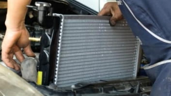 Technician inspecting car radiator during repair at Rob's Auto Repair.