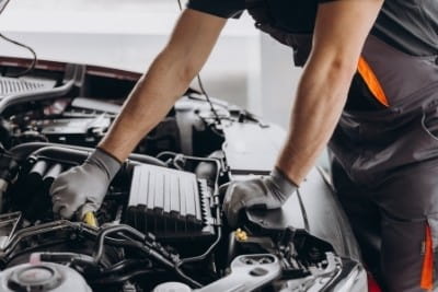 Technician inspecting car engine during repair at Rob's Auto Repair.