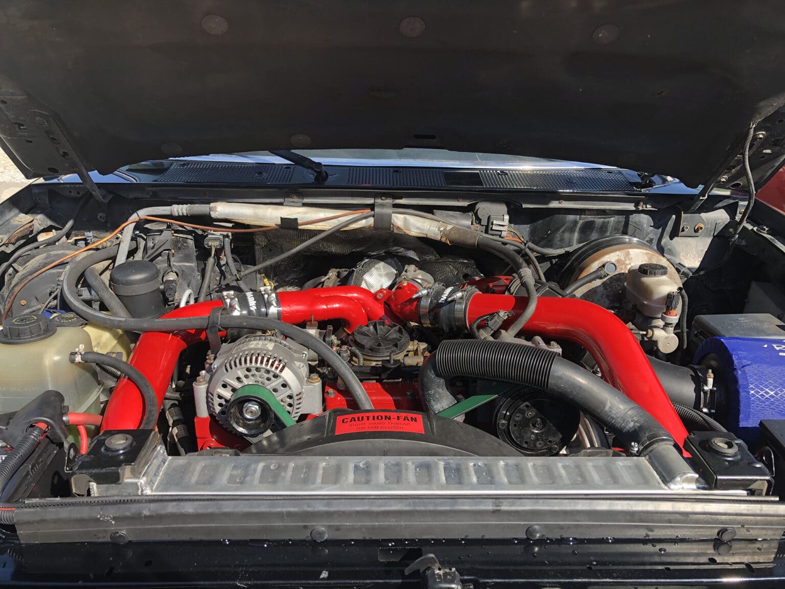 High-performance truck engine with red and black components under the hood. Expert auto repair servi.