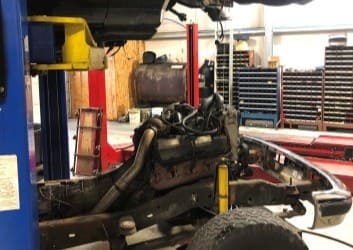Auto repair shop with engine being serviced on a vehicle lift.
