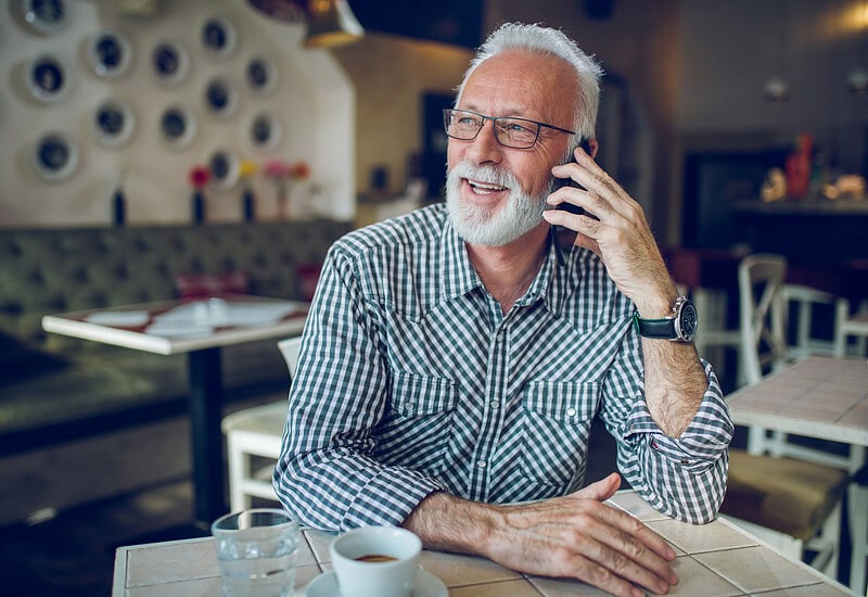 An image that shows Senior Man Using Smart Phone In Cafe