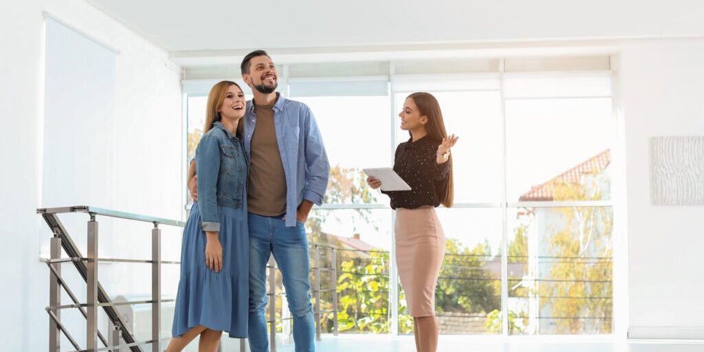 An image that shows Female Real Estate Agent Showing New House To Couple, Indoors
