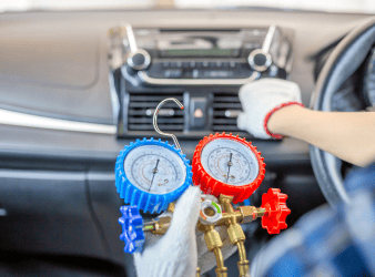 Technician performing air conditioning recharge in vehicle.