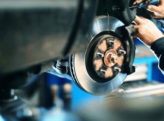 Mechanic inspecting car brake system during repair at Sam's Auto Repair.