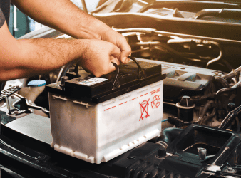 Technician replacing a car battery during auto repair service.