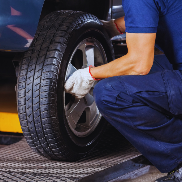 Technician changing a car tire during tire service at Sam's Auto Repair.