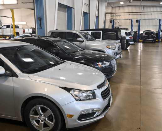 Auto repair shop with a variety of vehicles inside the service bay.