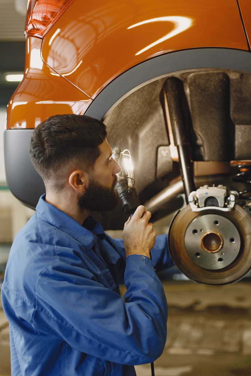 Auto mechanic inspecting brake system on a car at Sanfelippo Auto Repair.