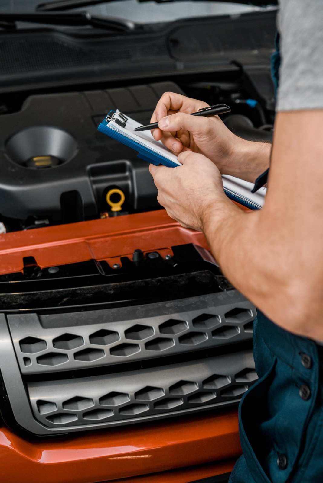 Auto mechanic inspecting engine and taking notes at Sanfelippo Auto Repair.
