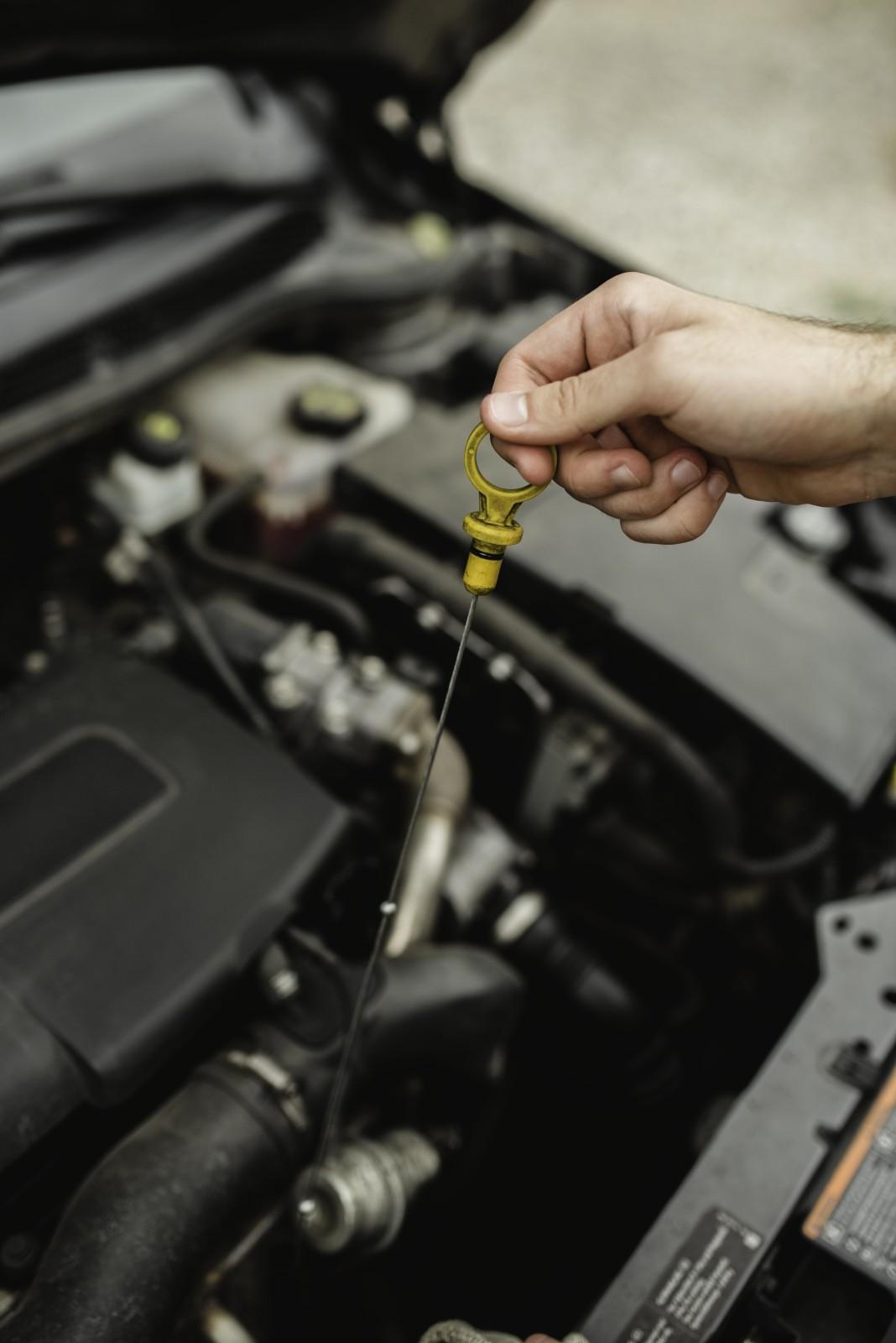 Person checking engine oil level with dipstick at Sanfelippo Auto Repair.