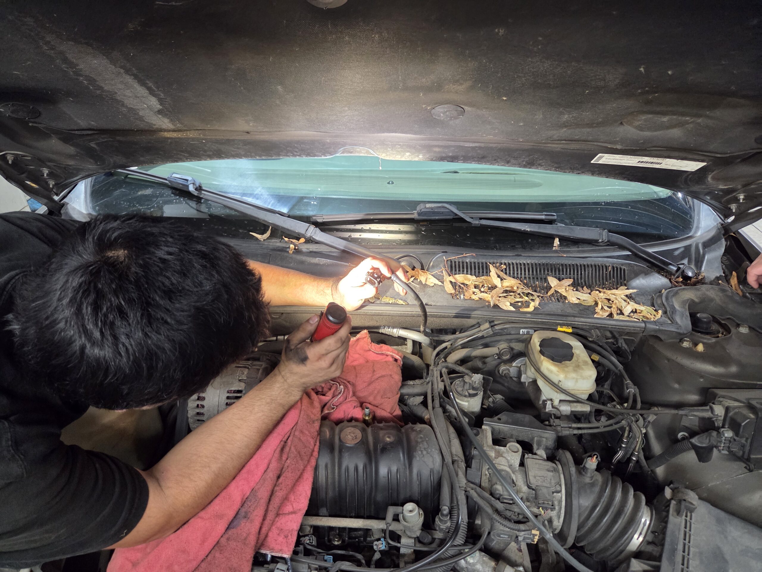 Mechanic diagnosing engine issues under the hood of a car.