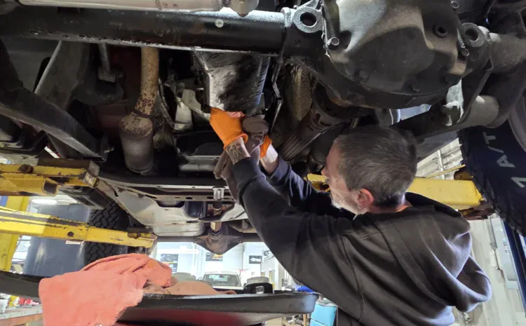 Mechanic working underneath a raised vehicle at Sanfelippo Auto Repair.