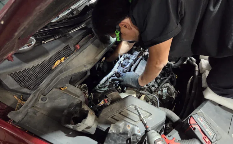 Technician repairing car engine at Sanfelippo Auto Repair with tools.