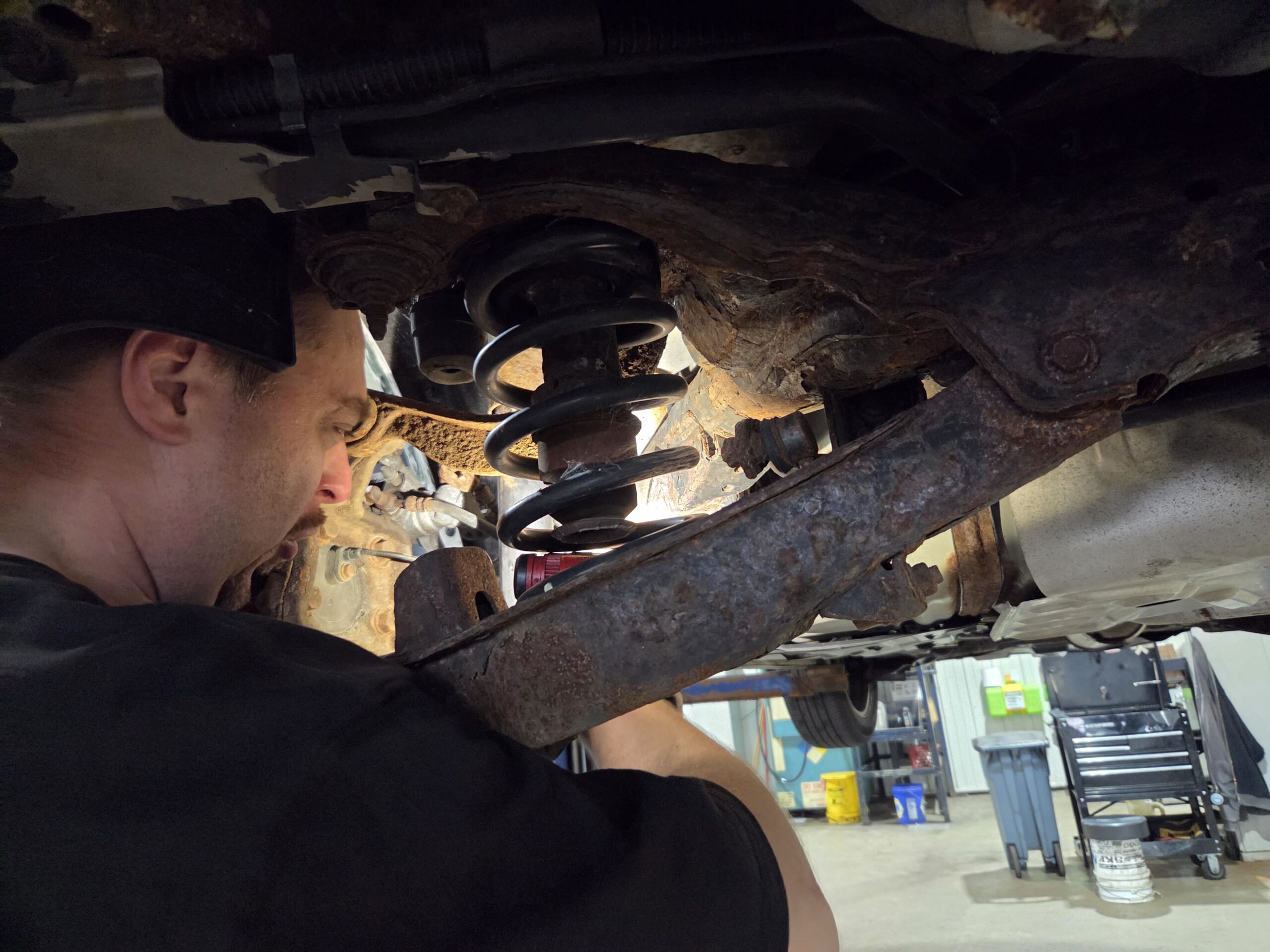 Technician inspecting vehicle undercarriage at Sanfelippo Auto Repair.
