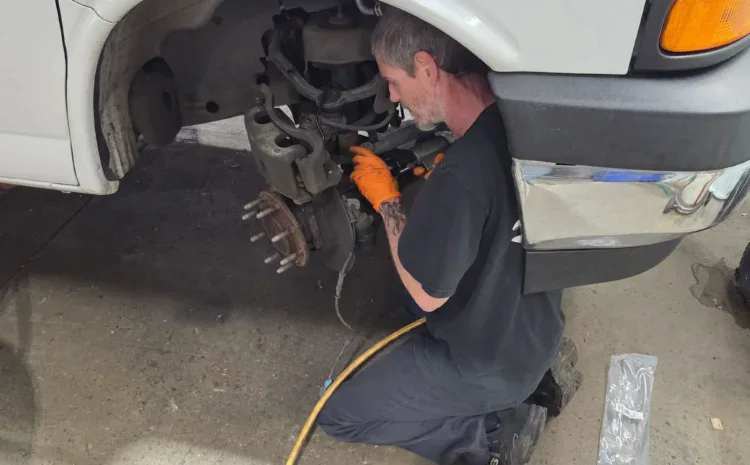 Automotive technician repairing vehicle wheel assembly at Sanfelippo Auto Repair.
