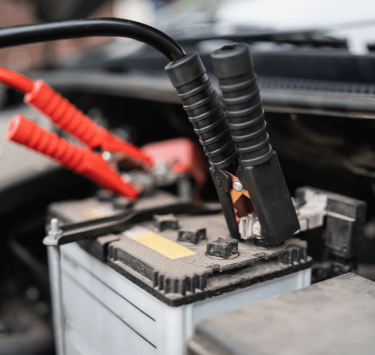 Jump-start cables on car battery for vehicle repair and diagnostics.