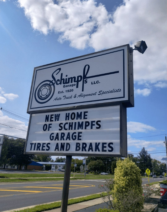 Exterior view of Schimpfs Garage sign advertising auto services in a sunny setting.