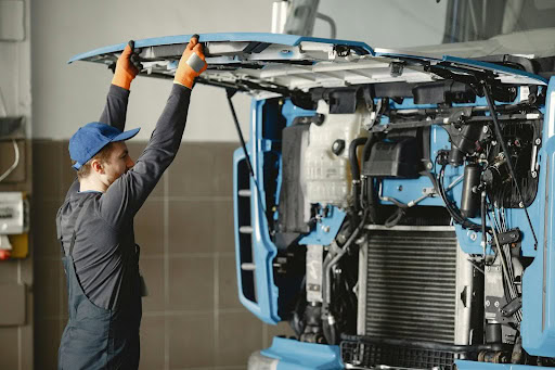 Heavy duty truck repair technician inspecting engine at Schimpfs Garage.