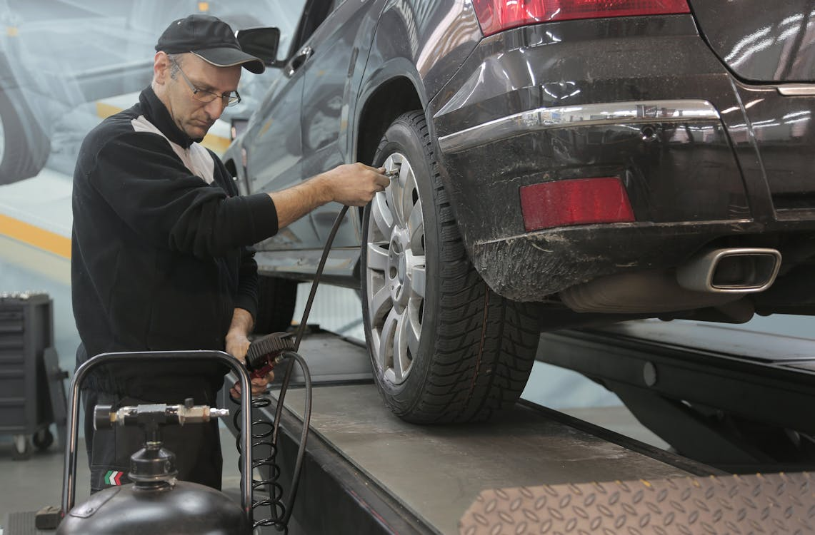 Automotive technician inspecting tire alignment on a vehicle to prevent uneven tire wear.
