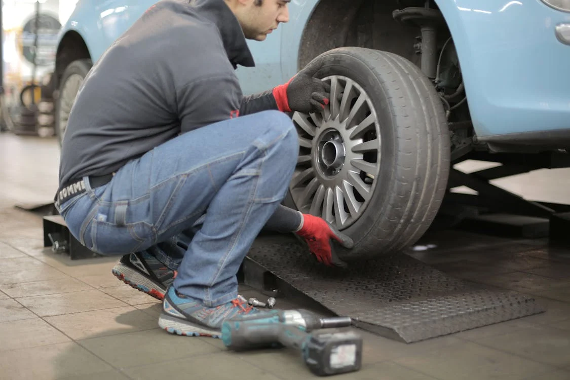 Technician inspecting a car tire for uneven wear and tear.