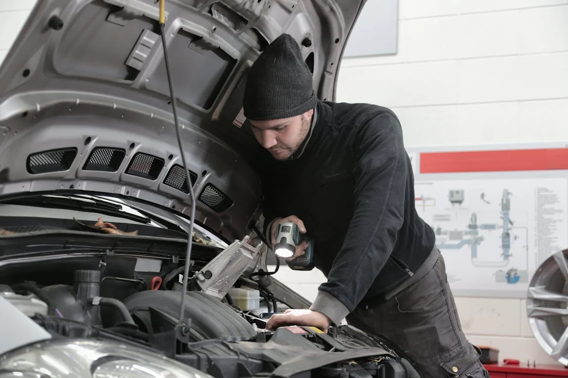 Man inspecting car engine to improve fuel efficiency with simple maintenance.