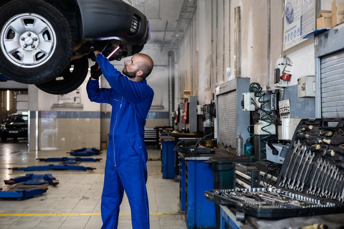 Vehicle maintenance technician inspecting a car in a modern garage.